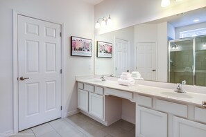 A modern bathroom with a white vanity, a large mirror, and a glass shower enclosure. - 7013ows 14 Bed 11 Bathroom (Davenport)