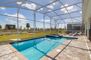 An outdoor swimming pool with a glass enclosure, surrounded by a patio area with lounge chairs and a hot tub. - 8915sd 8 Bedroom Resort Villa With Games R (Davenport)