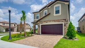 A two-story house with a stone facade, a dark garage door, and a well-maintained lawn. - 5569misty Luxury 7 Bedroom Pool Villa (Davenport)