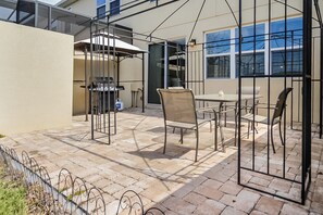 Een terras met een barbecue, buitentafel en stoelen.