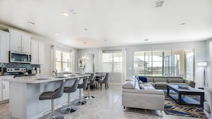 A spacious kitchen with a central island, bar stools, and a dining area. - Orlando Newest Resort Villa With Pool 1791spp (Kissimmee)