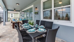 Un patio couvert avec une table à manger pour quatre personnes, entouré de chaises en osier.