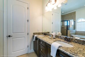 A bathroom with a granite countertop, a sink, a mirror, and a shower area. - Castle Pines 1080 Reunion (Kissimmee)