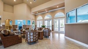 A spacious lobby with high ceilings, large windows, and a mix of seating areas including wicker sofas and patterned chairs. - Spacious & Modern 8 Bedroom 5 Bathroom Villa 508m (Kissimmee)