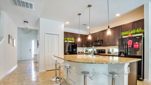 A modern kitchen with a large island, bar stools, stainless steel appliances, and pendant lighting. - Spacious & Modern 8 Bedroom 5 Bathroom Villa 508m (Kissimmee)