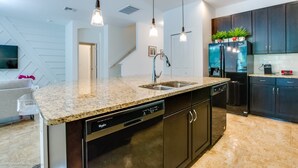 A modern kitchen with granite countertops, stainless steel appliances, and dark cabinetry. - Spacious & Modern 8 Bedroom 5 Bathroom Villa 508m (Kissimmee)