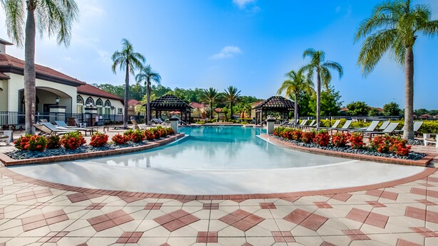 A swimming pool with lounge chairs and palm trees, surrounded by a tiled walkway. - Spacious & Modern 8 Bedroom 5 Bathroom Villa 508m (Kissimmee)