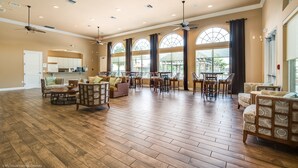 A spacious living room with hardwood flooring, multiple seating areas, and large windows offering views of the outdoors. - Spacious & Modern 8 Bedroom 5 Bathroom Villa 508m (Kissimmee)