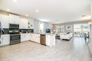 A modern kitchen with white cabinetry, stainless steel appliances, and a central island. - 1580pd New Amazing Champions Gate 8 Bedroom 5 Bed (Davenport)