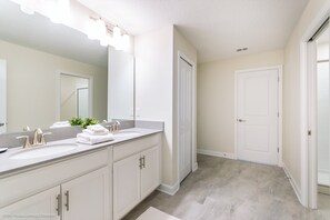 A bathroom with two sinks, a large mirror, and a door leading to another room. - 1580pd New Amazing Champions Gate 8 Bedroom 5 Bed (Davenport)