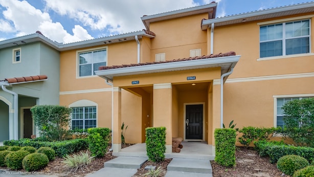 A two-story building with a beige facade, a covered entrance, and numbered doors 8962 and 8964. - Cuban Place 8963 Paradise Plams (Kissimmee)