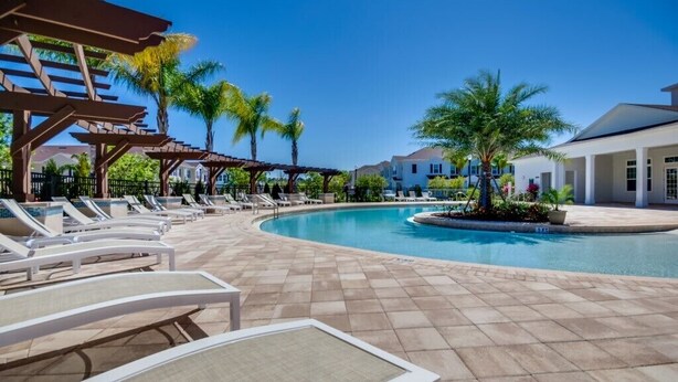 A pool area with lounge chairs and a pergola. - Lucaya Village Resort 4 Bedroom Townhome 2901 (Lake Buena Vista)