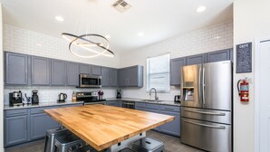 A modern kitchen with grey cabinets, stainless steel appliances, a wooden island with bar stools, and a pendant light. - Luxury 5 Bedroom 4 Bath Villa With Bespoke 468bel (Davenport)