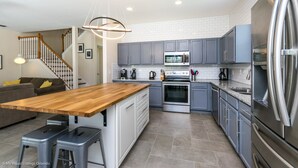 A modern kitchen with grey cabinets, stainless steel appliances, and a wooden island. - Luxury 5 Bedroom 4 Bath Villa With Bespoke 468bel (Davenport)