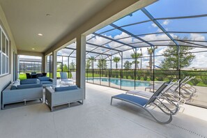 Un espacio al aire libre techado con piscina, sillas de descanso y asientos.