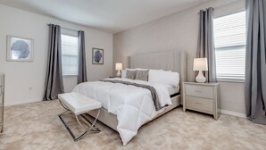 Ein Schlafzimmer mit einem Bett, Nachttischen, einer Bank und Kunstwerken an den Wänden.