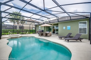 A swimming pool with a glass enclosure, lounge chairs, and a table with chairs. - 5BD 5BA Solterra Resort Luxury Villa 4175oak (Davenport)