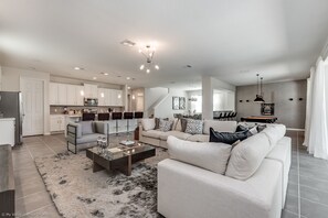 A modern living room with a sofa, coffee table, and a dining area with a chandelier. - Solara Resort 9 Bedroom 6 Bathroom Resort 9024srl (Kissimmee)