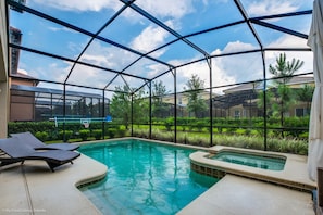 Un espace piscine doté d’une structure en verre, de chaises longues et d’un jacuzzi.