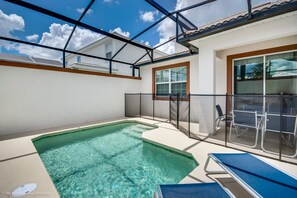 A swimming pool with a glass enclosure, a covered patio area, and a seating arrangement. - 8917stin New Luxury Furnished 5 Bedroom 4 Bathroom (Davenport)