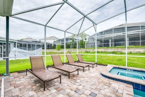 A covered outdoor area with lounge chairs and a pool.