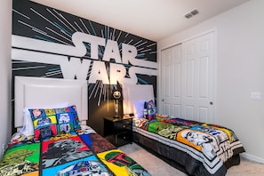 Ett sovrum med Star Wars-tema, med två sängar, en väggmålning och ett nattduksbord.
