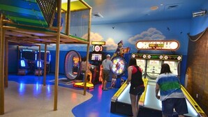 An indoor arcade with various gaming machines and a play area. - Clabria Villa Regal Palms (Davenport)