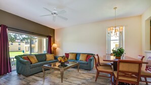A spacious living room with a sofa, coffee table, and dining area. - Clabria Villa Regal Palms (Davenport)