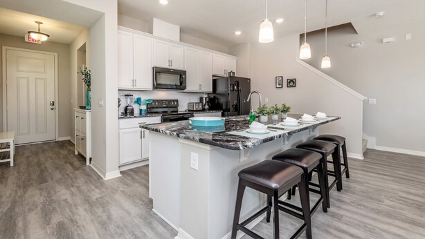 A modern kitchen with white cabinets, a central island with stools, a microwave, and a refrigerator. - 5153ad Amazing Compass Baytown Home Sleeps 10 (Kissimmee)