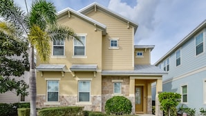 A two-story house with a beige exterior, stone accents, and a front porch.