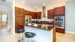 A modern kitchen with wooden cabinets, stainless steel appliances, and a central island with bar stools.