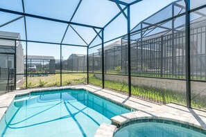 A swimming pool with a glass enclosure, surrounded by a metal fence, and a view of a residential area. - Egret Mills Villa Solara (Kissimmee)