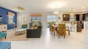A modern open-plan living and dining area with a kitchen, featuring a ceiling fan, a dining table with chairs, and a kitchen island. - 9037hs 6 Bedroom 6 Bathroom Champions Gate Villa (Davenport)