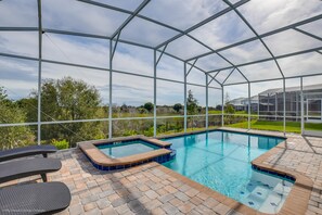 A swimming pool with a glass enclosure, surrounded by a brick patio and lounge chairs. - 1571pw Amazing Champions Gate 6 Bedroom 6 Bed (Davenport)