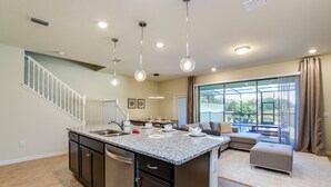 A spacious kitchen with a large island, dark cabinetry, and pendant lighting. - 4659terra (Davenport)