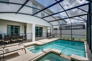A swimming pool with a glass enclosure, lounge chairs, and a patio area. - 4720shd Ultimate New 6 Bedroom Storey Lake Home (Kissimmee)