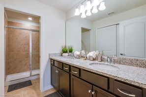 A bathroom with a shower, double sink vanity, and a large mirror. - Terra Sonnessta Drive Villa Solterra 1 (Davenport)
