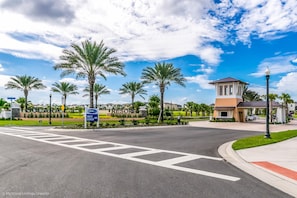 A street view at a resort with palm trees, a clear sky, and a sign for the sales center. - Carribean View Villa Solara (Kissimmee)
