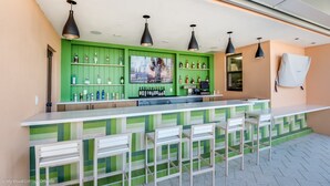 A bar area with green cabinetry, multiple hanging pendant lights, and bar stools. - Carribean View Villa Solara (Kissimmee)