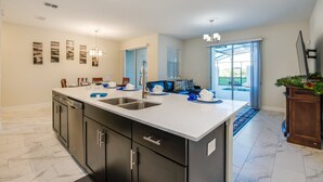 A modern kitchen with a large island, dark cabinetry, and a view to the outside. - Stinger Drive villa 8953 Champions Gate (Davenport)