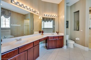 A bathroom with a large vanity, double sinks, and a mirror with lights.