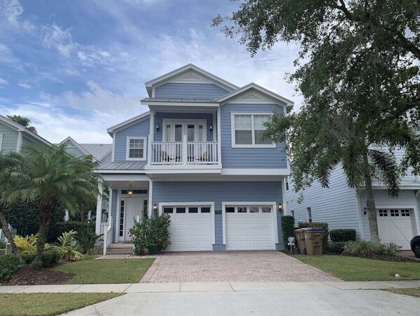 A two-story residential house with a front porch, a balcony on the upper floor, and two garage doors.