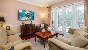 A living room with a large window, a painting, a wooden coffee table, and a sofa. - 7704ll Ultimate Reunion Home (Kissimmee)