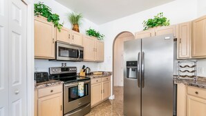A modern kitchen with stainless steel appliances, light wood cabinets, and a marble floor. - 215glen Amazing Newly Decorated 5 Bedroom (Davenport)