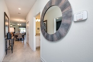 A modern hallway with a round mirror, a keypad lock, and a dining area with a patterned tablecloth. - 910pb Luxury Furnished 5 Bedroom 5 Bathroom (Davenport)