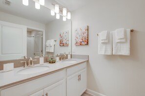 A bathroom with two sinks, a large mirror, and wall-mounted towels. - Lullaby Lane Villa Storey Lake (Kissimmee)