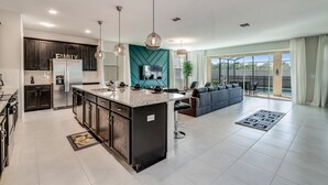 Una cocina moderna con armarios oscuros, una isla central y un comedor con sofá y sillas.