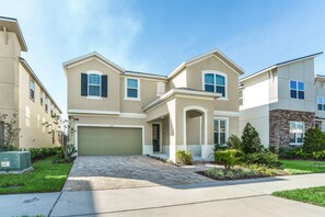 A two-story residential building with a garage, a driveway, and landscaped gardens. - 1822cvt New 9 Bedroom 6 Bathroom Resort Villa (Kissimmee)