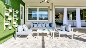 A modern outdoor living area with a sofa set, a coffee table, and a ceiling fan. - 1798cvt Solara Resort 9 Bedroom 6 Bathroom Villa (Kissimmee)