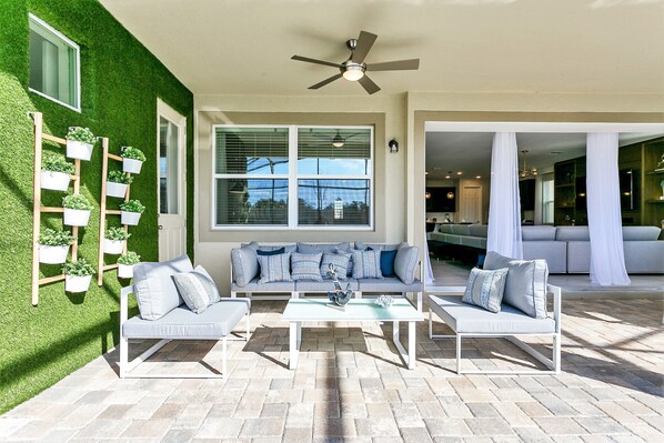 A modern outdoor living area with a sofa set, a coffee table, and a ceiling fan.